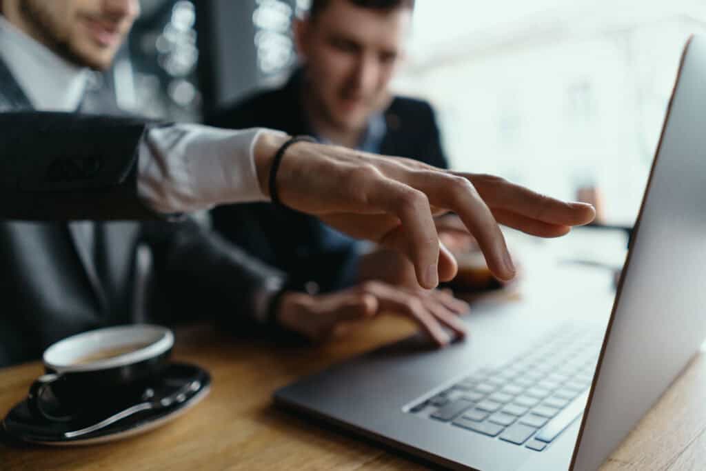 Dos hombres de negocios están hablando y señalando la pantalla del portátil mientras discuten. Negocio. Tecnología. Camaradería.